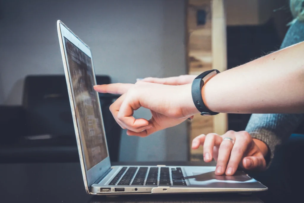 Hand pointing towards Computer screen